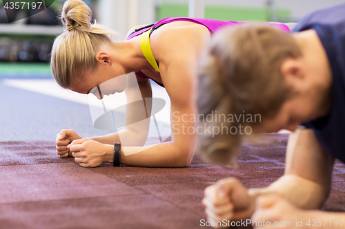 Image of woman and man doing plank exercise in gym