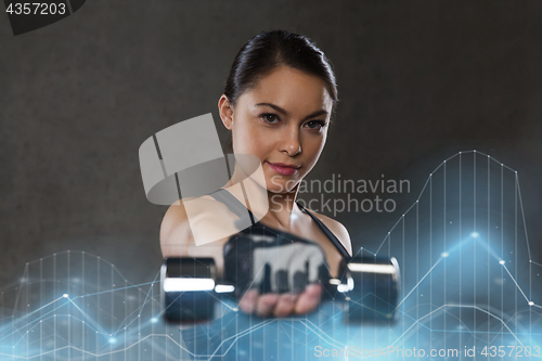 Image of young woman flexing muscles with dumbbells in gym