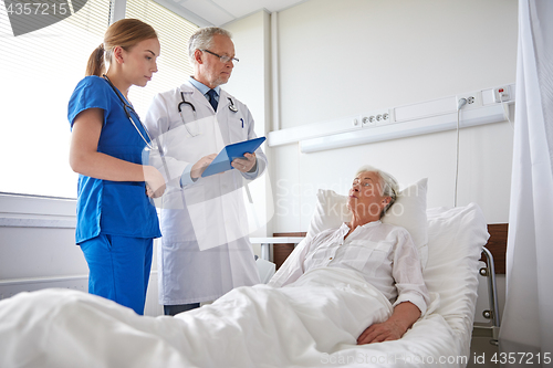 Image of doctor and nurse visiting senior woman at hospital