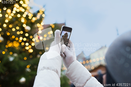 Image of hands with smartphone photographing christmas tree