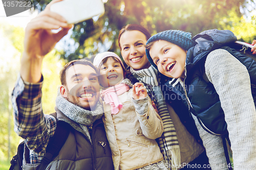 Image of family with backpacks taking selfie by smartphone