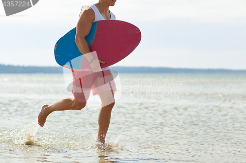 Image of happy young man with skimboard on summer beach