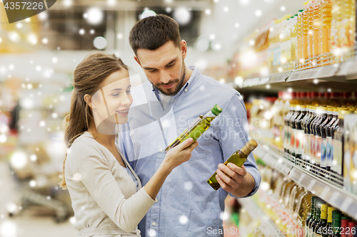 Image of happy couple buying olive oil at grocery store