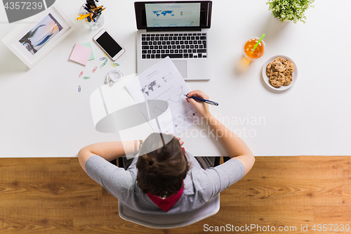 Image of woman with laptop and papers at office table