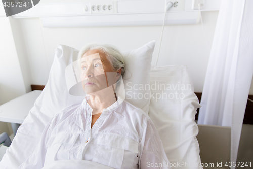 Image of sad senior woman lying on bed at hospital ward