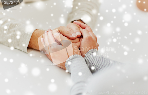 Image of close up of old man and young woman holding hands