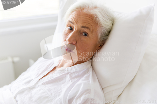 Image of sad senior woman lying on bed at hospital ward