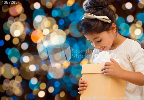 Image of smiling little girl with gift box over lights