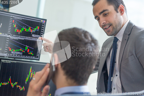 Image of Stock brokers looking at computer screens, trading online.