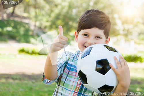 Image of Cute Young Boy Playing with Soccer Ball and Thumbs Up Outdoors i