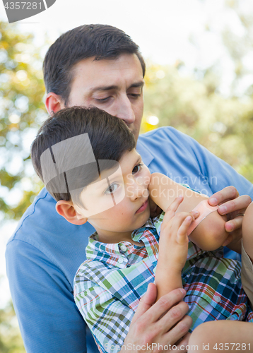 Image of Loving Father Puts a Bandage on the Elbow of His Young Son in th