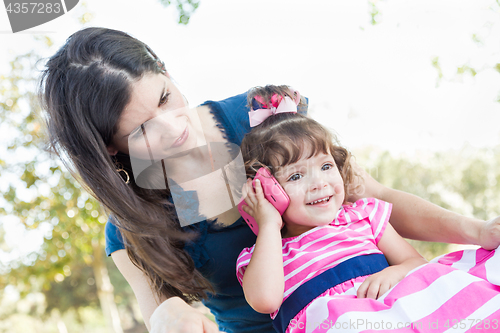 Image of Mixed Race Mother and Cute Baby Daughter Playing with Cell Phone