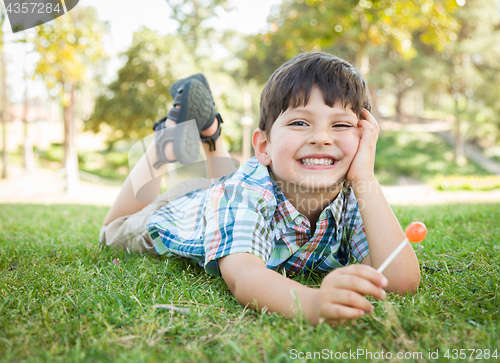 Image of Handsome Young Boy Enjoying His Lollipop Outdoors on the Grass.