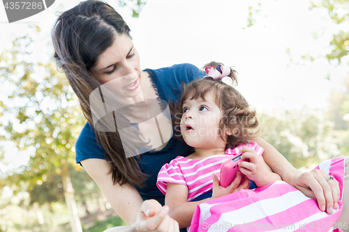 Image of Mixed Race Mother and Cute Baby Daughter Playing with Cell Phone