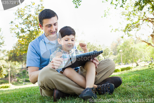 Image of Happy Father and Son Playing on a Computer Tablet Outside.