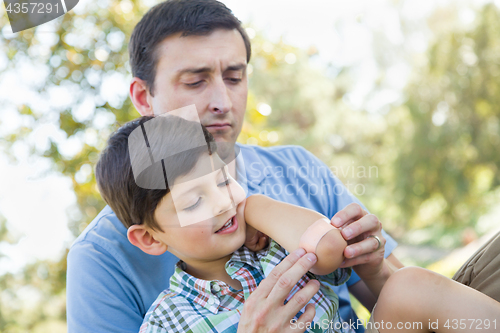 Image of Loving Father Puts a Bandage on the Elbow of His Young Son in th