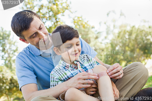 Image of Loving Father Puts a Bandage on the Elbow of His Young Son in th