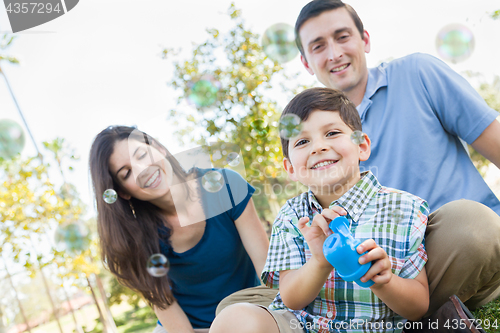 Image of Young Boy Blowing Bubbles with His Parents in the Park.