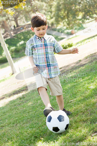 Image of Cute Young Boy Playing with Soccer Ball Outdoors in the Park.