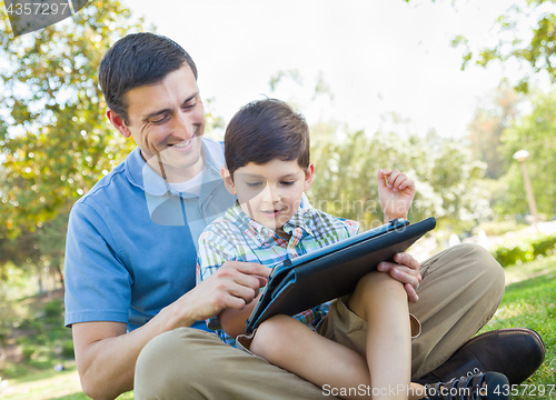 Image of Happy Father and Son Playing on a Computer Tablet Outside.