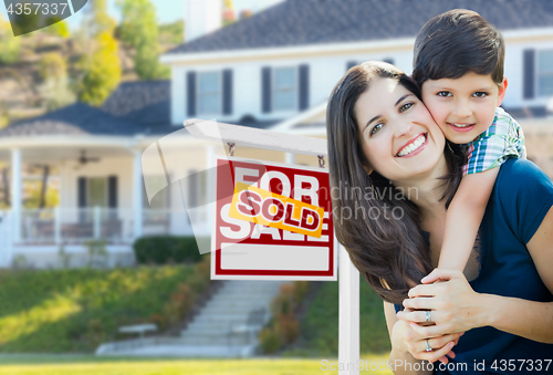 Image of Young Mother and Son In Front of Sold For Sale Real Estate Sign 