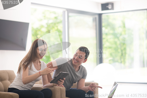 Image of couple relaxing at  home with tablet and laptop computers