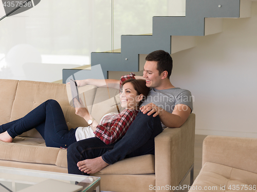 Image of couple relaxing at  home with tablet computers