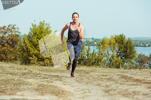 Image of Running sport. Man runner sprinting outdoor in scenic nature. Fit muscular male athlete training trail running for marathon run.