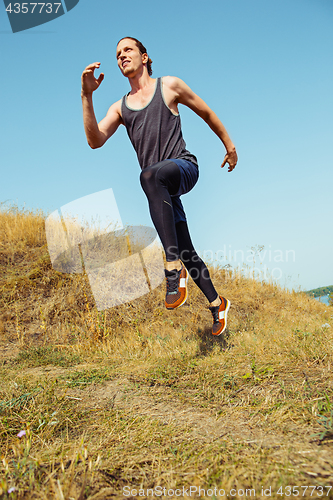 Image of Running sport. Man runner sprinting outdoor in scenic nature. Fit muscular male athlete training trail running for marathon run.