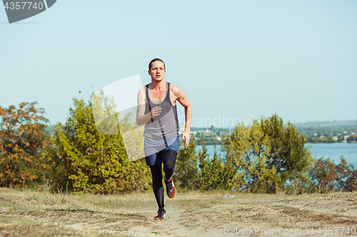 Image of Running sport. Man runner sprinting outdoor in scenic nature. Fit muscular male athlete training trail running for marathon run.