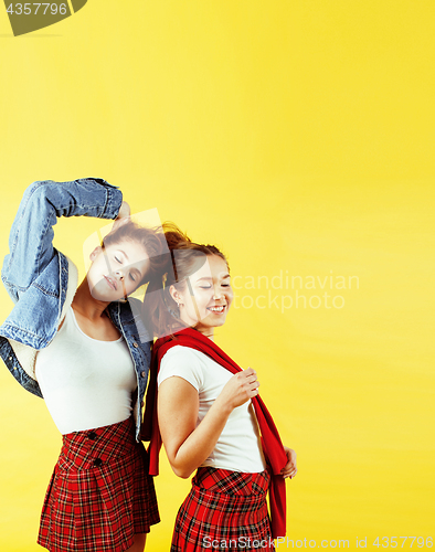 Image of lifestyle people concept: two pretty young school teenage girls having fun happy smiling on yellow background 