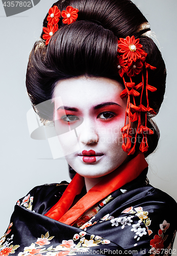 Image of young pretty geisha in black kimono among sakura, asian ethno close up