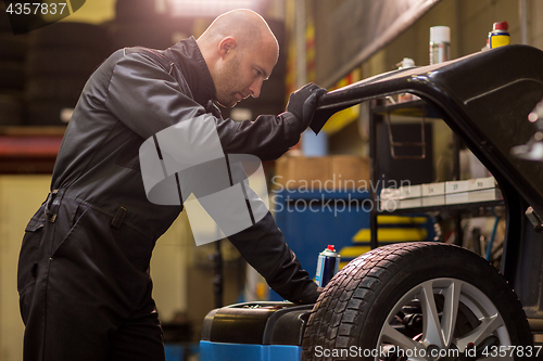 Image of auto mechanic balancing car wheel at workshop