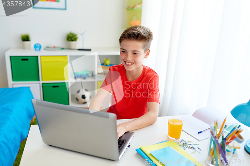 Image of student boy typing on laptop computer at home