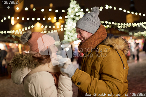 Image of happy couple holding hands at christmas tree