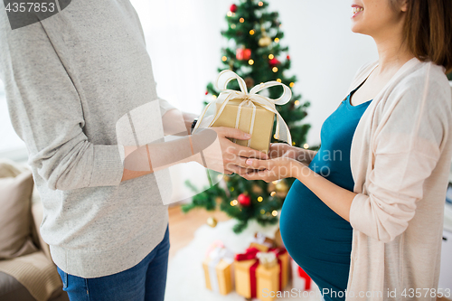 Image of husband giving christmas present to pregnant wife