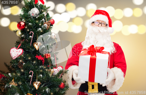 Image of santa claus with gift box at christmas tree