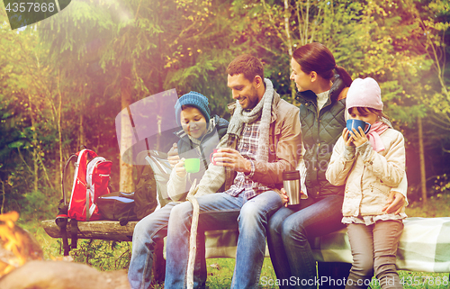 Image of happy family sitting on bench at camp fire