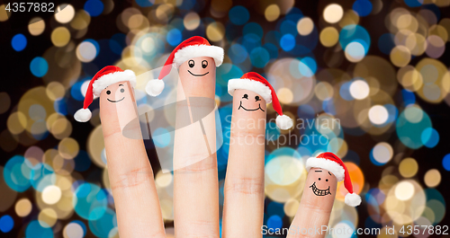 Image of close up of fingers in santa hats at christmas