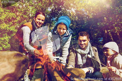 Image of happy family roasting marshmallow over campfire