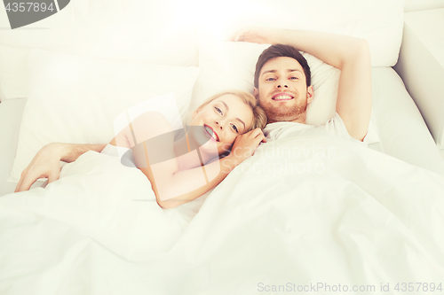 Image of happy couple lying in bed at home