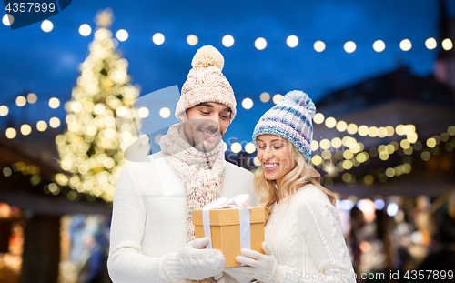 Image of happy couple with gift box over christmas lights