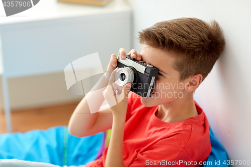 Image of happy boy with film camera photographing at home