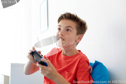 Image of happy boy with gamepad playing video game at home