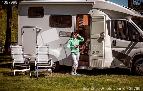 Image of Woman is standing with a mug of coffee near the camper RV.