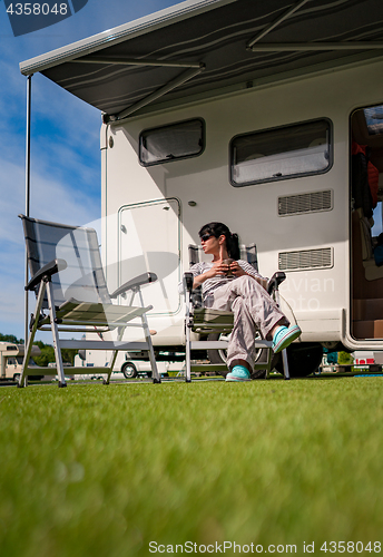 Image of Woman is standing with a mug of coffee near the camper RV.