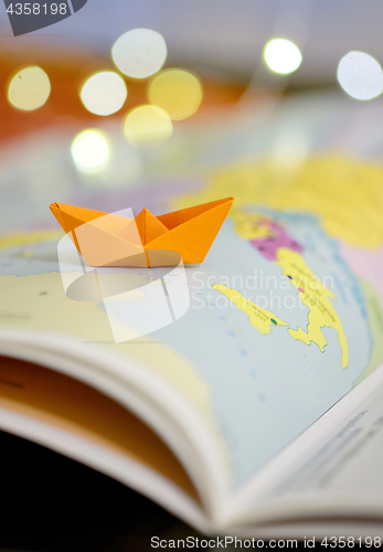 Image of Paper boat on a atlas book 