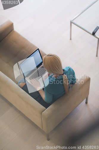 Image of Young woman using laptop at home