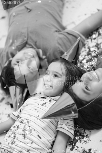 Image of kids  blowing confetti while lying on the floor