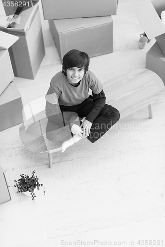 Image of boy sitting on the table with cardboard boxes around him top vie